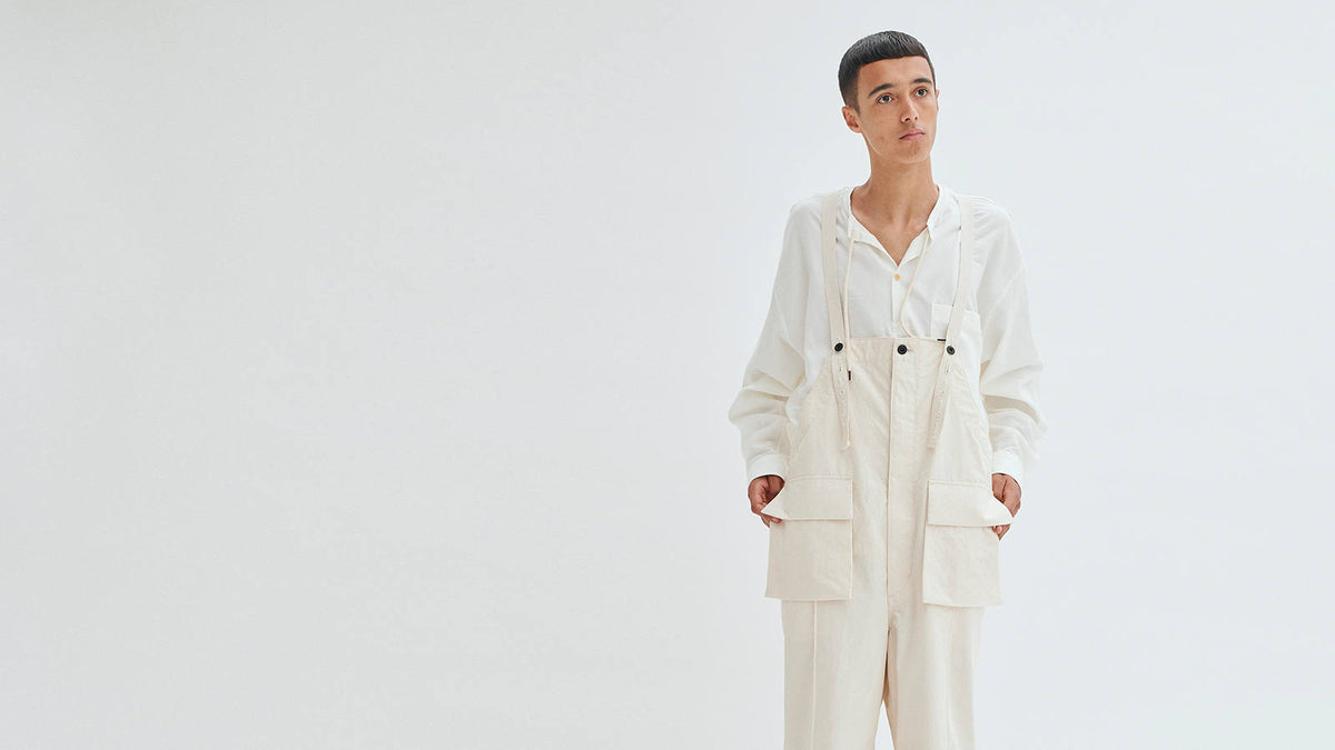 A model in a white shirt with ecru dungarees against a white background