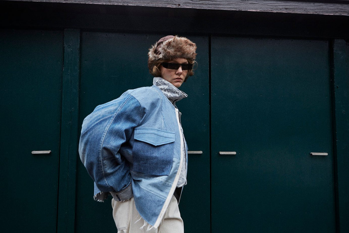 Side view of a fur hat with a panelled denim blouson